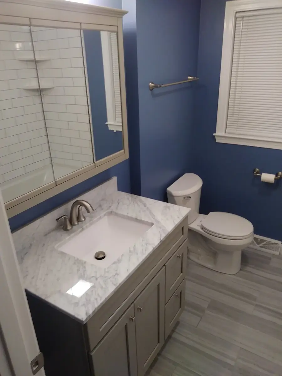 Remodeled bathroom with gray vanity, marble top and blue walls